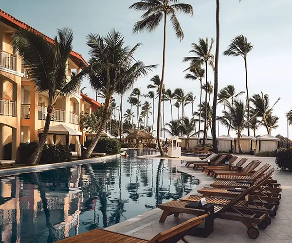 A resort in Punta Cana with deck chairs, pool, and palm trees