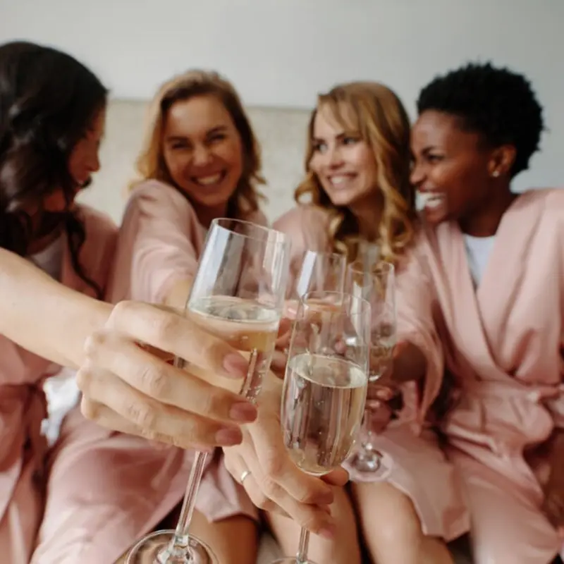 4 bridesmaids in pink robes toasting champagne