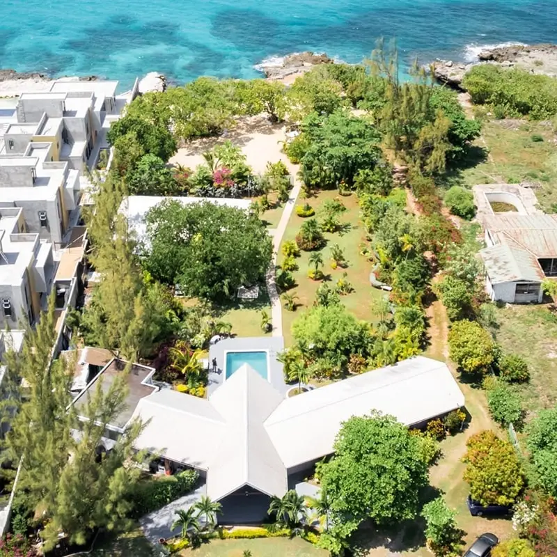 An overhead view of the Borhinvilla property showing lush green trees, a V-shaped building, and the ocean.