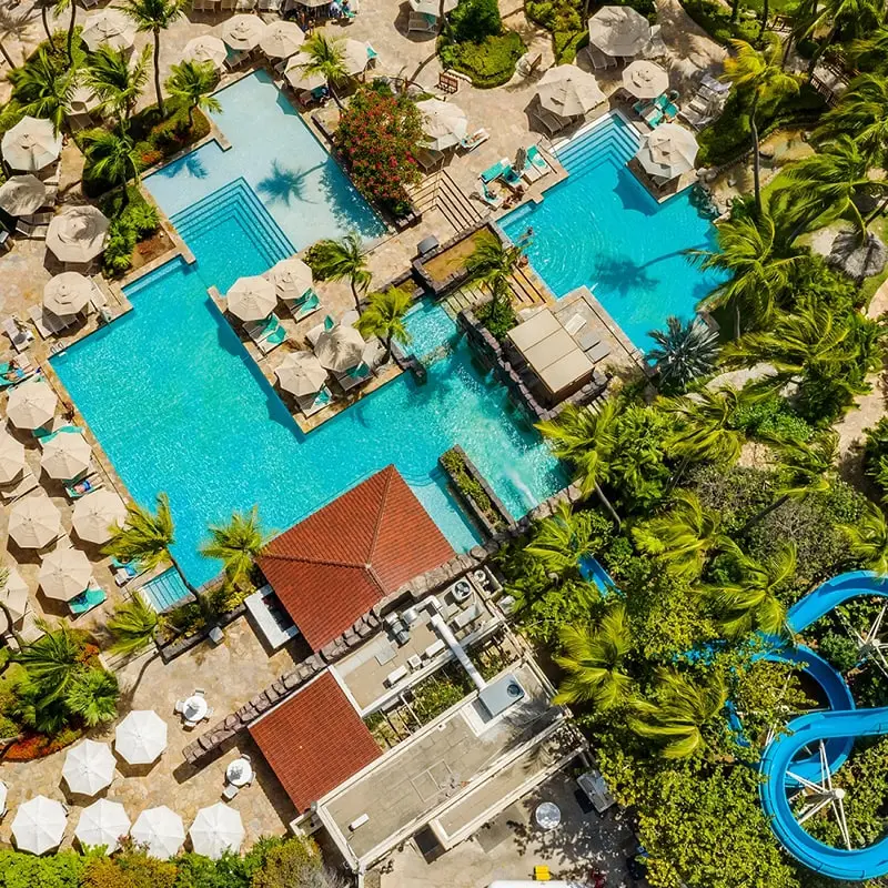 Aerial view of Hyatt Regency Aruba with blue pools, red roofs and greenery
