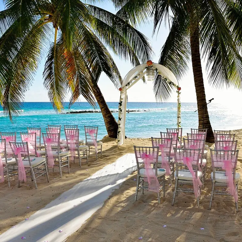 Tropical beach destination wedding in Barbados with altar and chairs lining the aisle