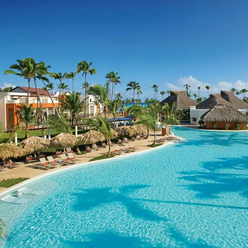 Exterior of Breathless Punta Cana with suites, large pool, and palm trees.