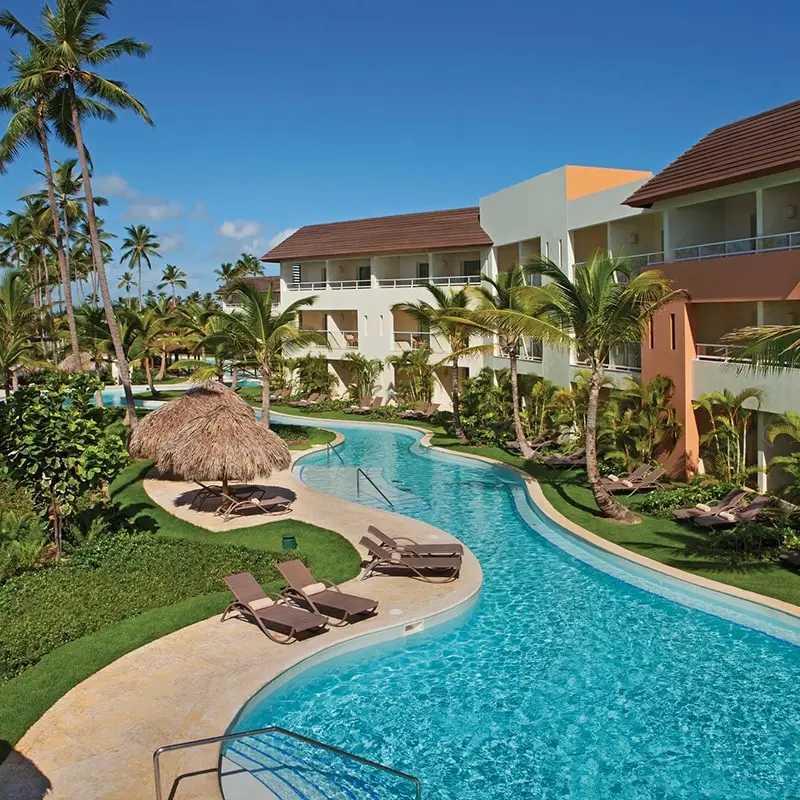 The exterior of the Dreams Royal Beach resort, with winding pool and palm trees.