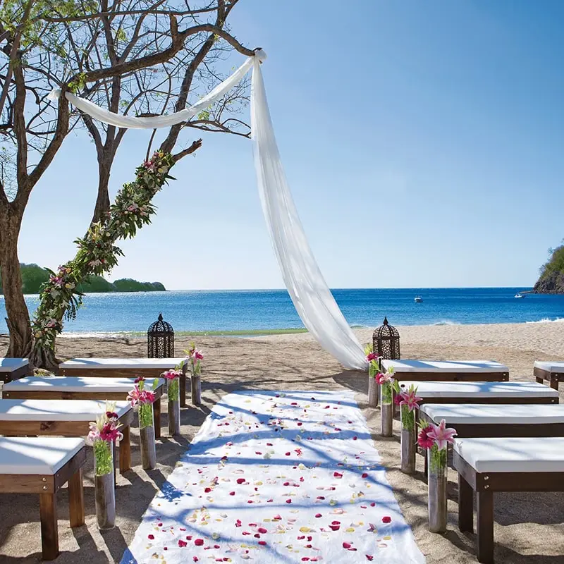 A simple drape of white cloth marks the wedding altar on the tropical beach.