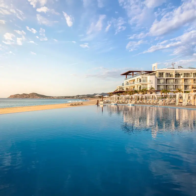 A large pool of blue leads up to the exterior of Le Blanc Spa Resort Los Cabos