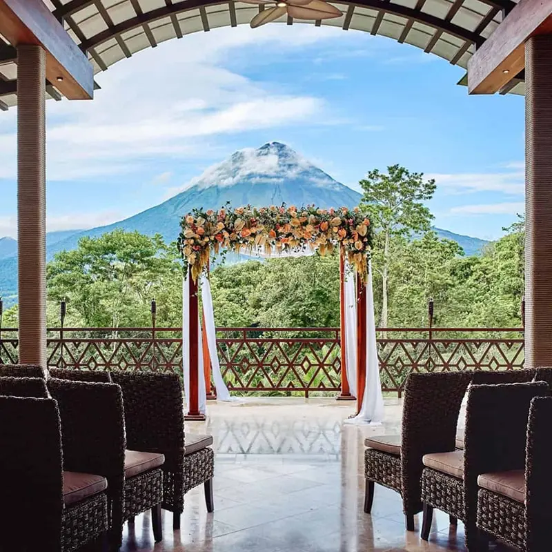 Arenal Volcano rises in the distance, in the foreground is a decorated altar and seats for guests.