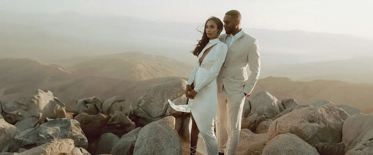 A wedding couple stand on a mountain in their urban chic attire