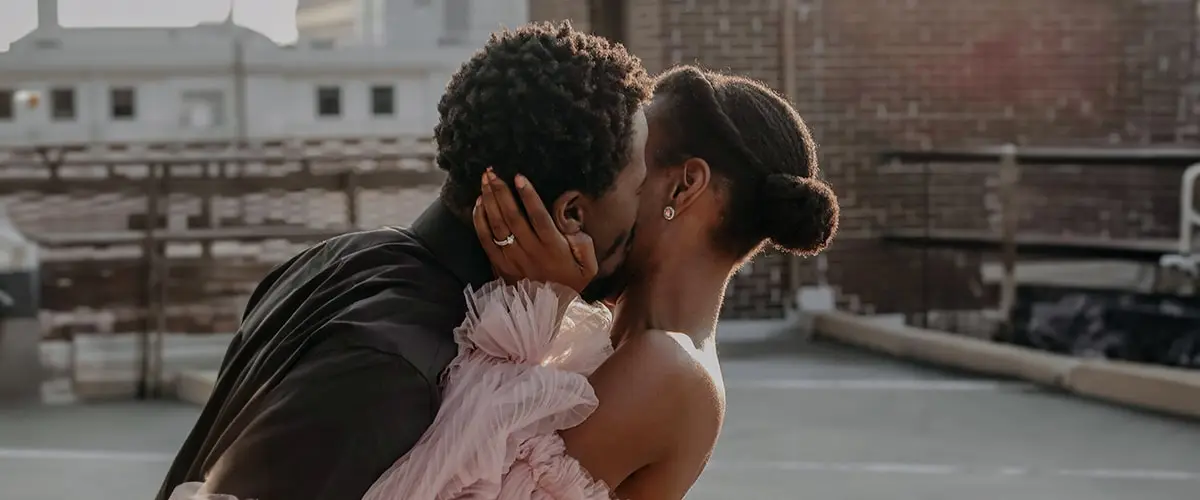 A couple is kissing in an urban chic setting on their wedding day