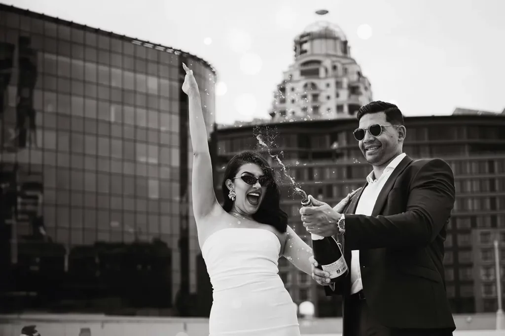 A couple pop a bottle of champagne in an urban chic setting on their wedding day