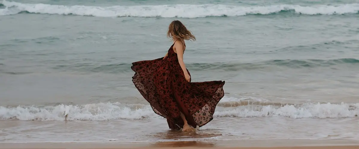 A bride on a beach in a flowy red dress showing the changing fashion trends